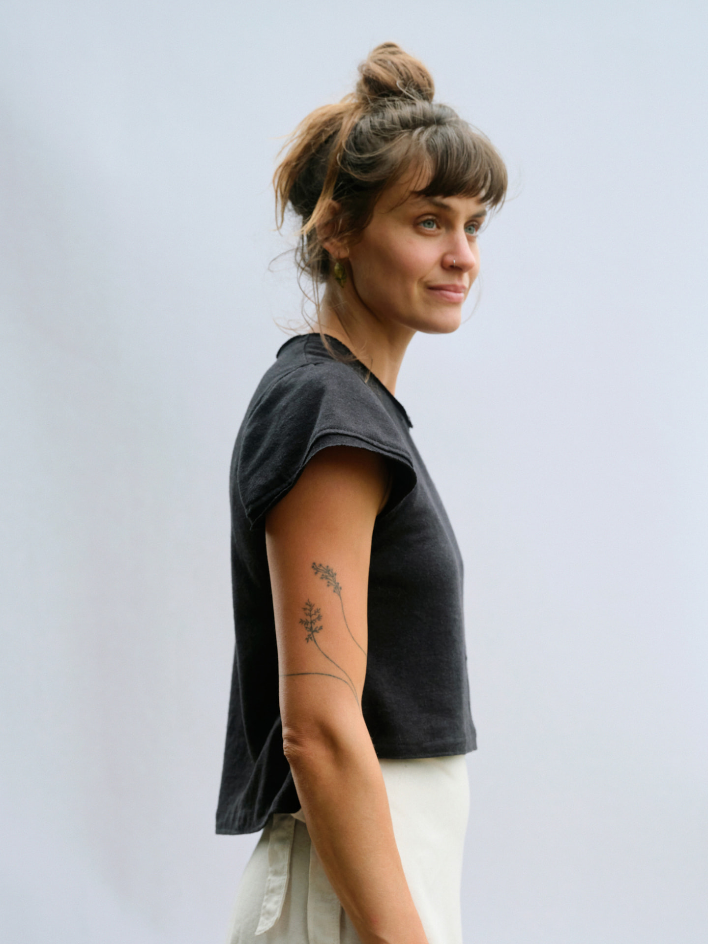Woman wearing the Truth-T short sleeve T-shirt in charcoal, side profile showing the relaxed cut and capped sleeve